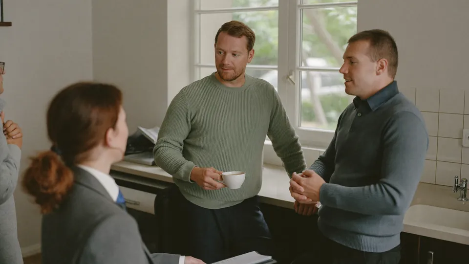 An illustrative small team talking in a bright office kitchen