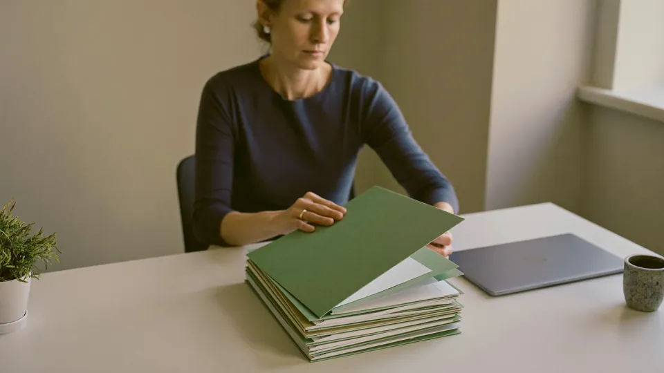 An illustrative tidy office, a neat stack of folders being squared on a clear desk